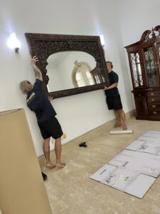 Two professional shin movers both holding a big wall mirror